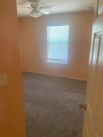 an empty room with a chandelier fan and windows