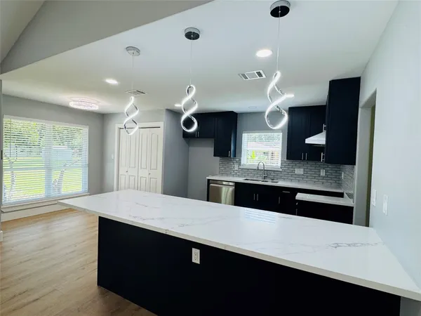 a large kitchen with stainless steel appliances a large counter top a stove and a refrigerator