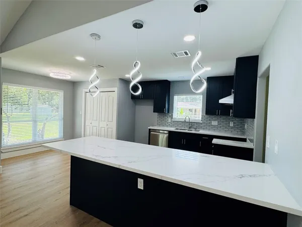 a large kitchen with stainless steel appliances a large counter top a stove and a refrigerator