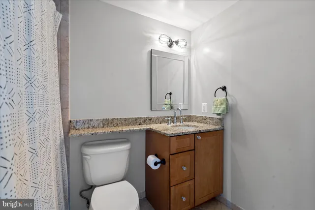 a bathroom with a granite countertop toilet a sink and a mirror