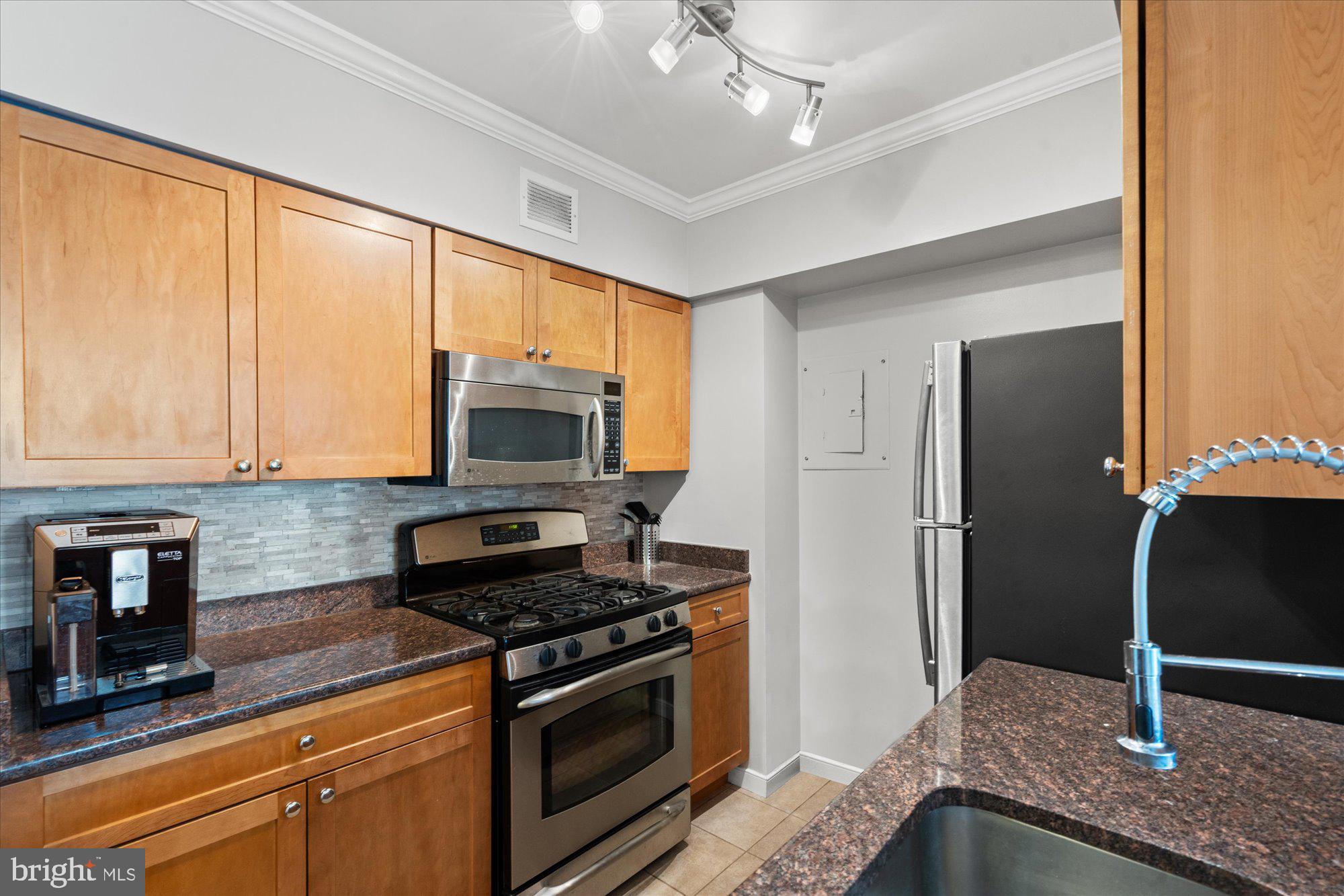 4801 Fairmont Avenue, Unit 705 Bethesda, MD 20814 - Photo 6 of 19 a kitchen with stainless steel appliances granite countertop a refrigerator a stove and a sink with wooden floor