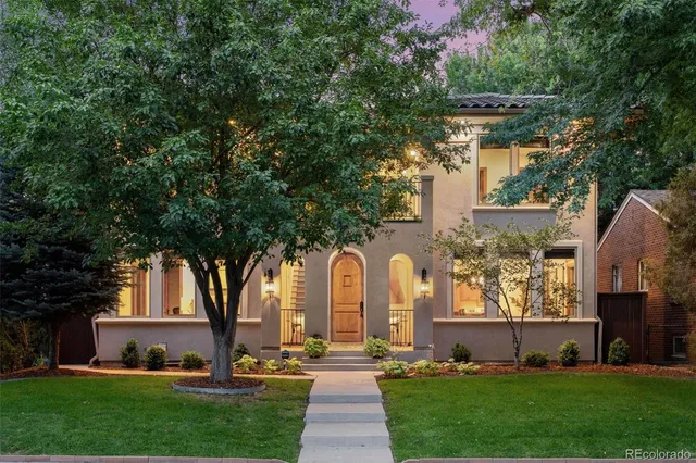 a front view of a house with garden and trees