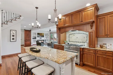 a kitchen with stainless steel appliances granite countertop a stove a kitchen island a dining table and chairs with wooden floor