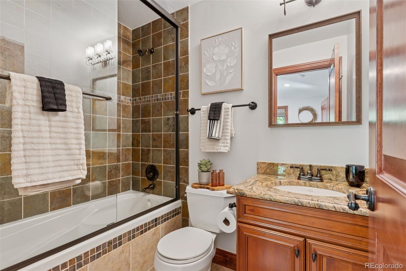 1026 South Cook Street Denver, CO 80209 - Photo 28 of 41 a bathroom with a granite countertop toilet a sink and bathtub