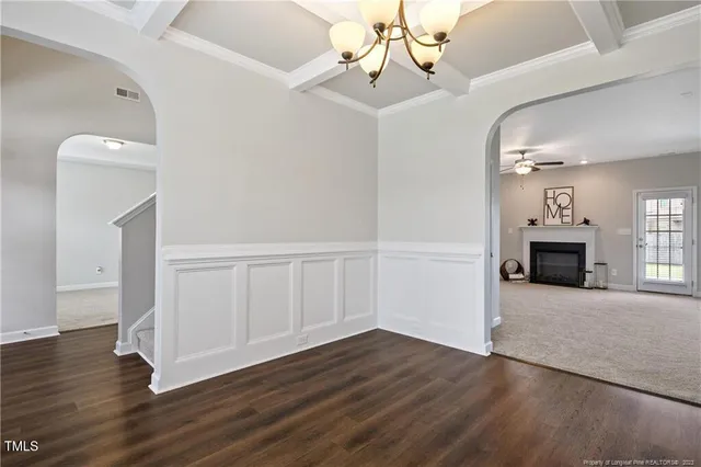 an empty room with wooden floor fireplace and windows