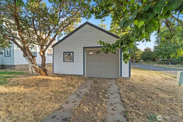 a view of a house with a yard and large tree