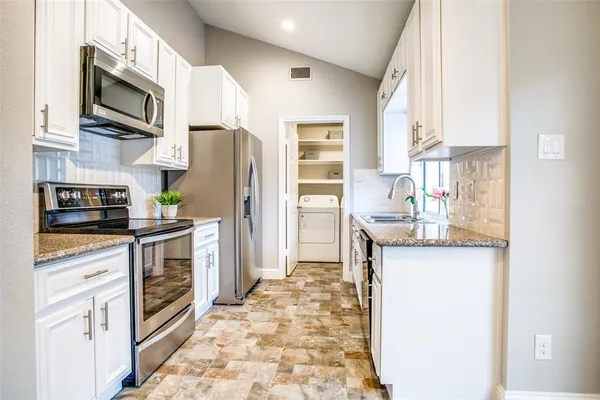 a kitchen with stainless steel appliances granite countertop a refrigerator stove and sink