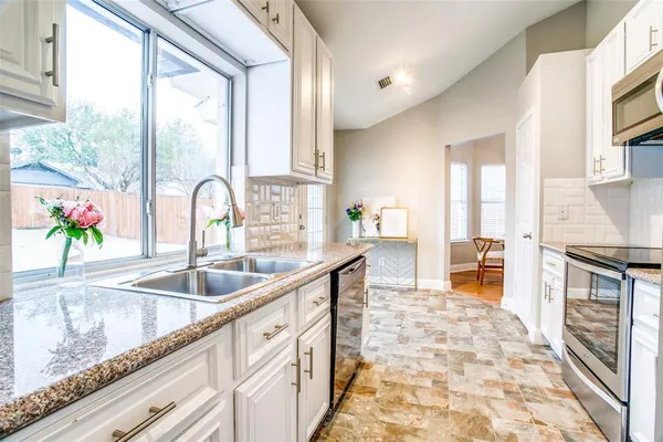 a kitchen with granite countertop a stove a sink and a counter space