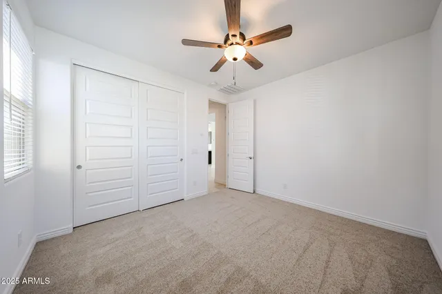 an empty room with closet and fan