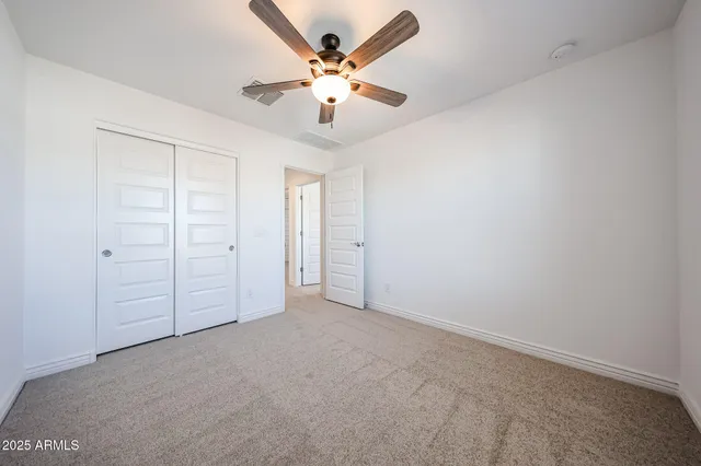 an empty room with closet and fan
