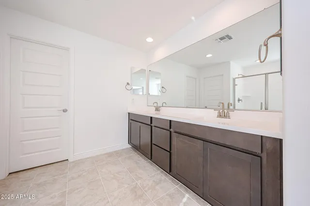 a bathroom with a double vanity sink a mirror and a shower