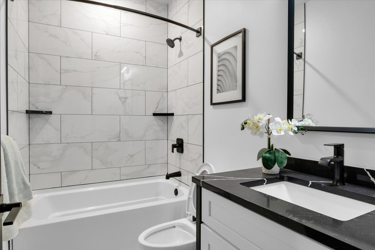 4235 South Champlain Avenue, Unit 1N Chicago, IL 60653 - Photo 19 of 26 a bathroom with a granite countertop sink a toilet and bathtub
