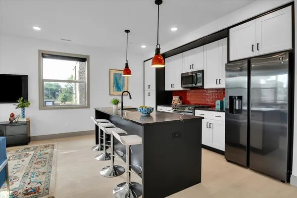 a kitchen with stainless steel appliances granite countertop a sink refrigerator and microwave