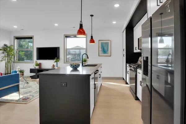 a kitchen with stainless steel appliances kitchen island granite countertop a refrigerator and a sink