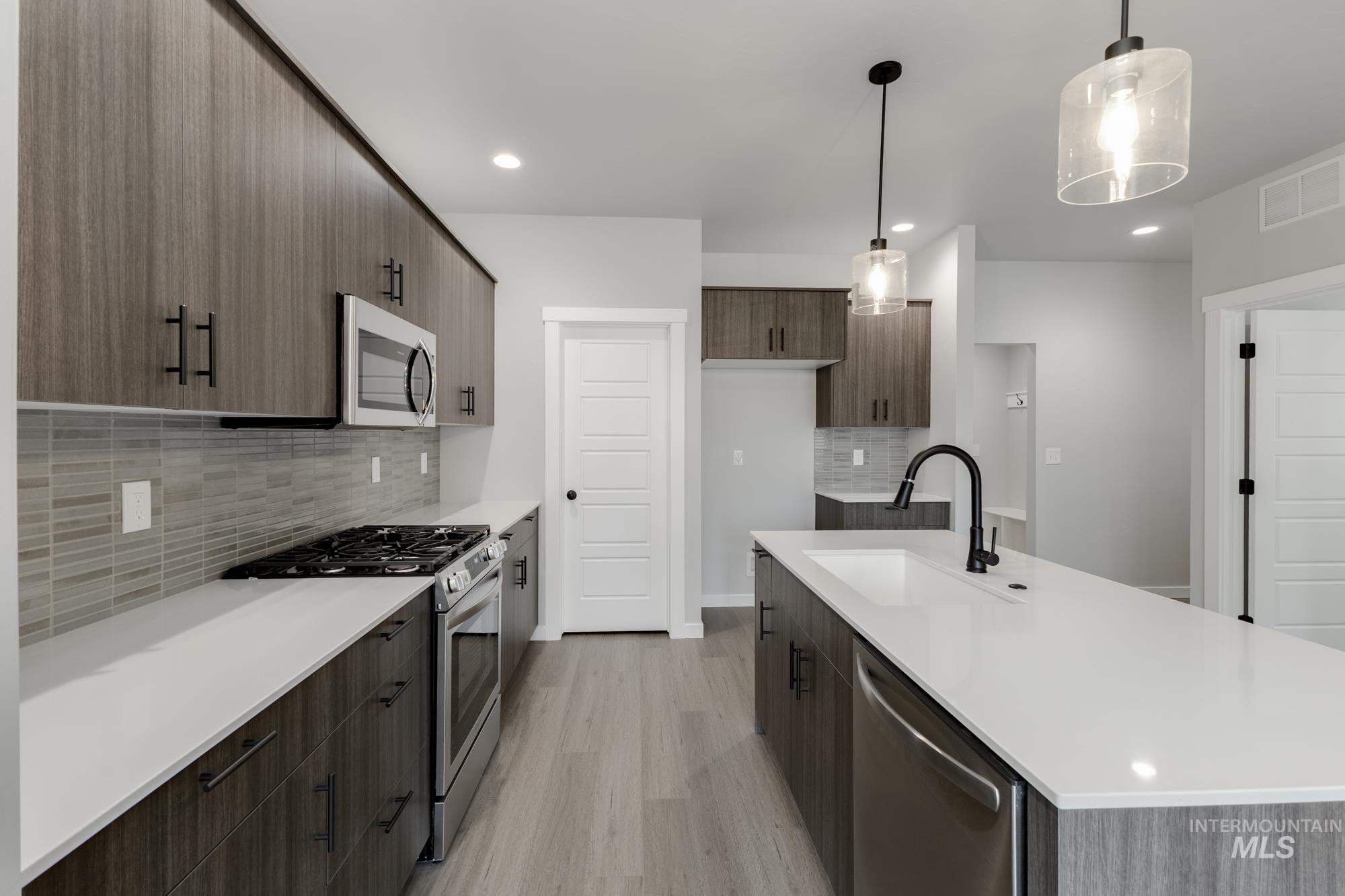 3672 West Dover Drive Meridian, ID 83642 - Photo 5 of 23 Kitchen featuring appliances with stainless steel finishes, pendant lighting, light wood finished floors, tasteful backsplash, and modern cabinets