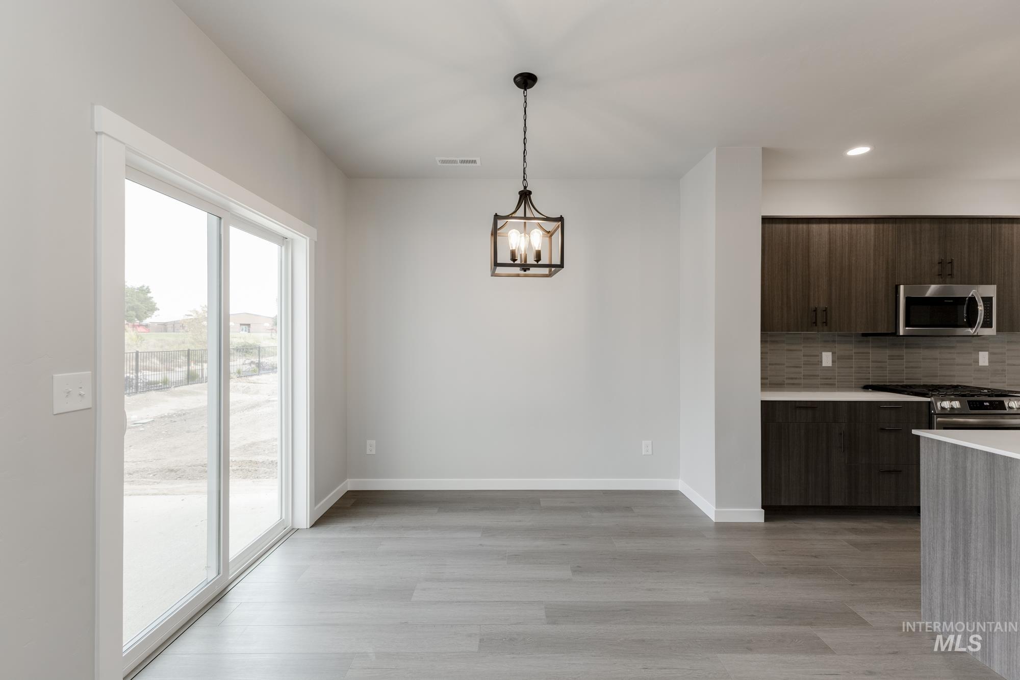 3672 West Dover Drive Meridian, ID 83642 - Photo 6 of 23 Kitchen with modern cabinets, backsplash, stainless steel appliances, light wood finished floors, and decorative light fixtures