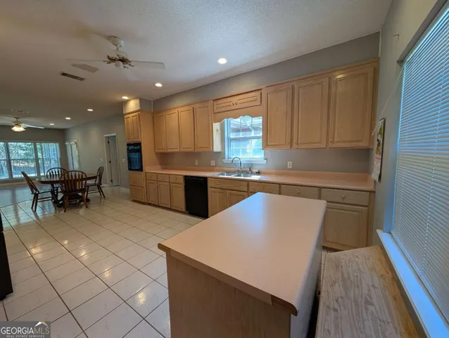 a kitchen with stainless steel appliances granite countertop a sink a stove a refrigerator and island with wooden floor