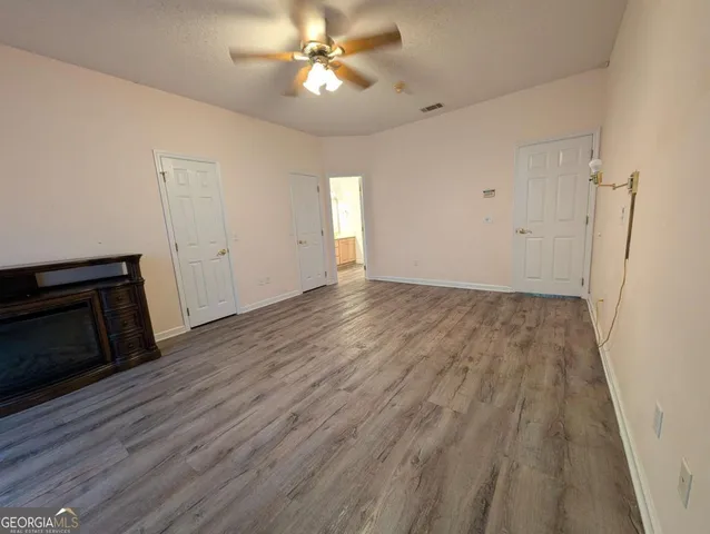 an empty room with wooden floor and a ceiling fan