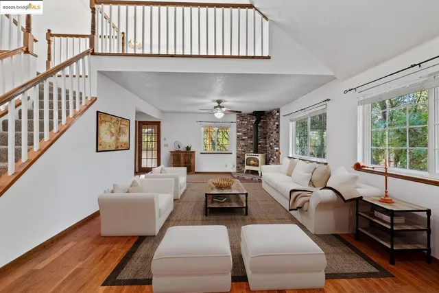 a view of an empty room with wooden floor stairs and a window