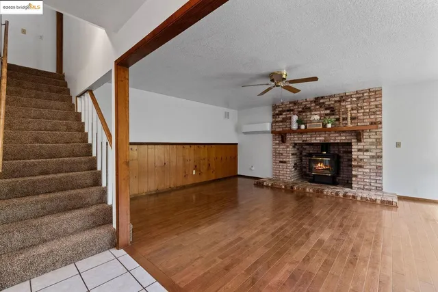 a view of an empty room with wooden floor fireplace and a window