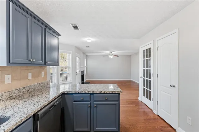 a kitchen with granite countertop cabinets stainless steel appliances a sink and wooden floor