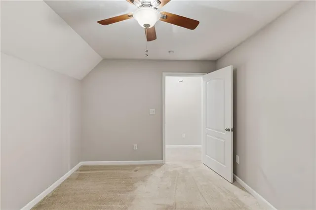 an empty room with a ceiling fan and carpet