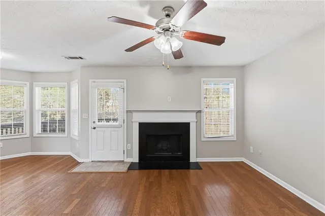 an empty room with windows fireplace and wooden floor