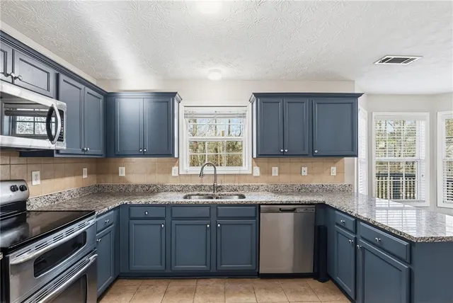 a kitchen with granite countertop stainless steel appliances a sink window and cabinets
