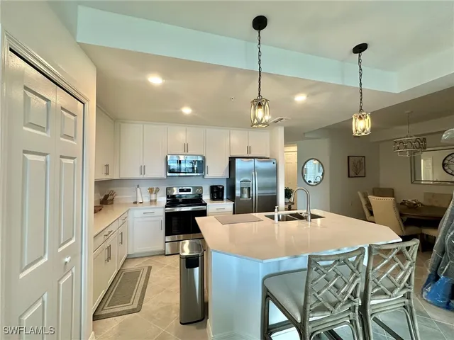 a kitchen with stainless steel appliances kitchen island granite countertop a dining table chairs and white cabinets