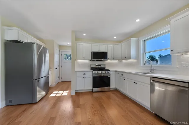a kitchen with granite countertop a refrigerator stove and wooden floor