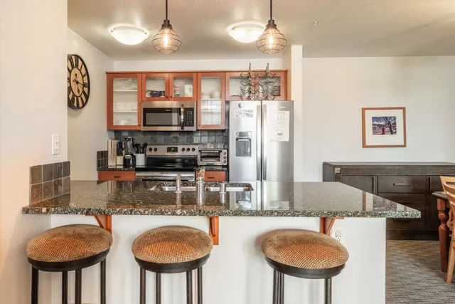 a kitchen with stainless steel appliances granite countertop a sink a stove and a refrigerator