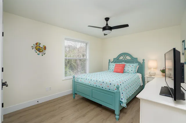 a bedroom with a bed a couch and a flat tv screen on the dresser