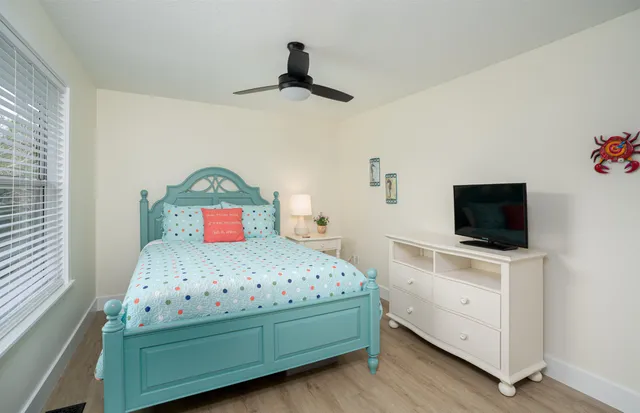a bedroom with a bed and a flat tv screen on the dresser
