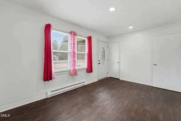 an empty room with entryway and wooden floor