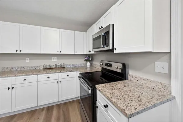 a kitchen with granite countertop white cabinets and a stove