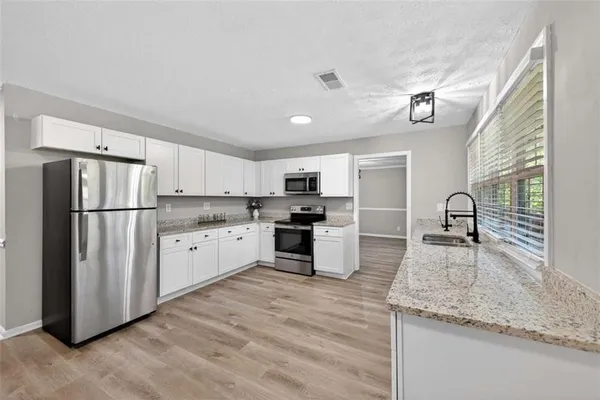 a kitchen with granite countertop a refrigerator and a sink