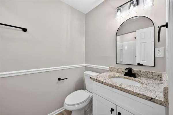 a bathroom with a granite countertop sink a toilet mirror and vanity