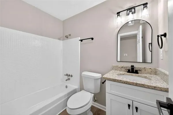 a bathroom with a granite countertop toilet sink and mirror
