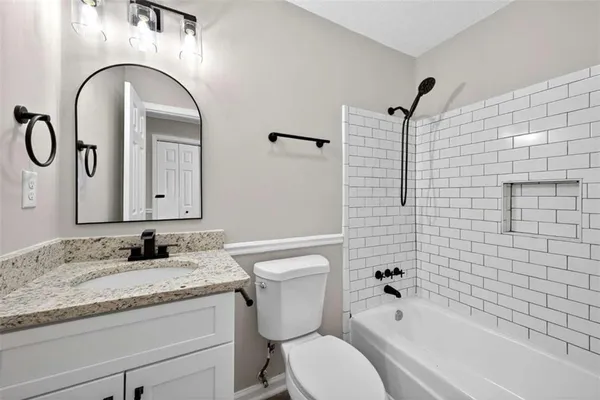 a bathroom with a granite countertop toilet a sink and a bathtub