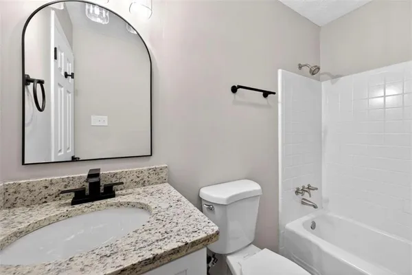 a bathroom with a granite countertop sink toilet and shower