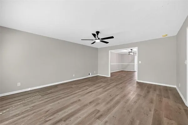 a view of empty room with wooden floor and ceiling fan
