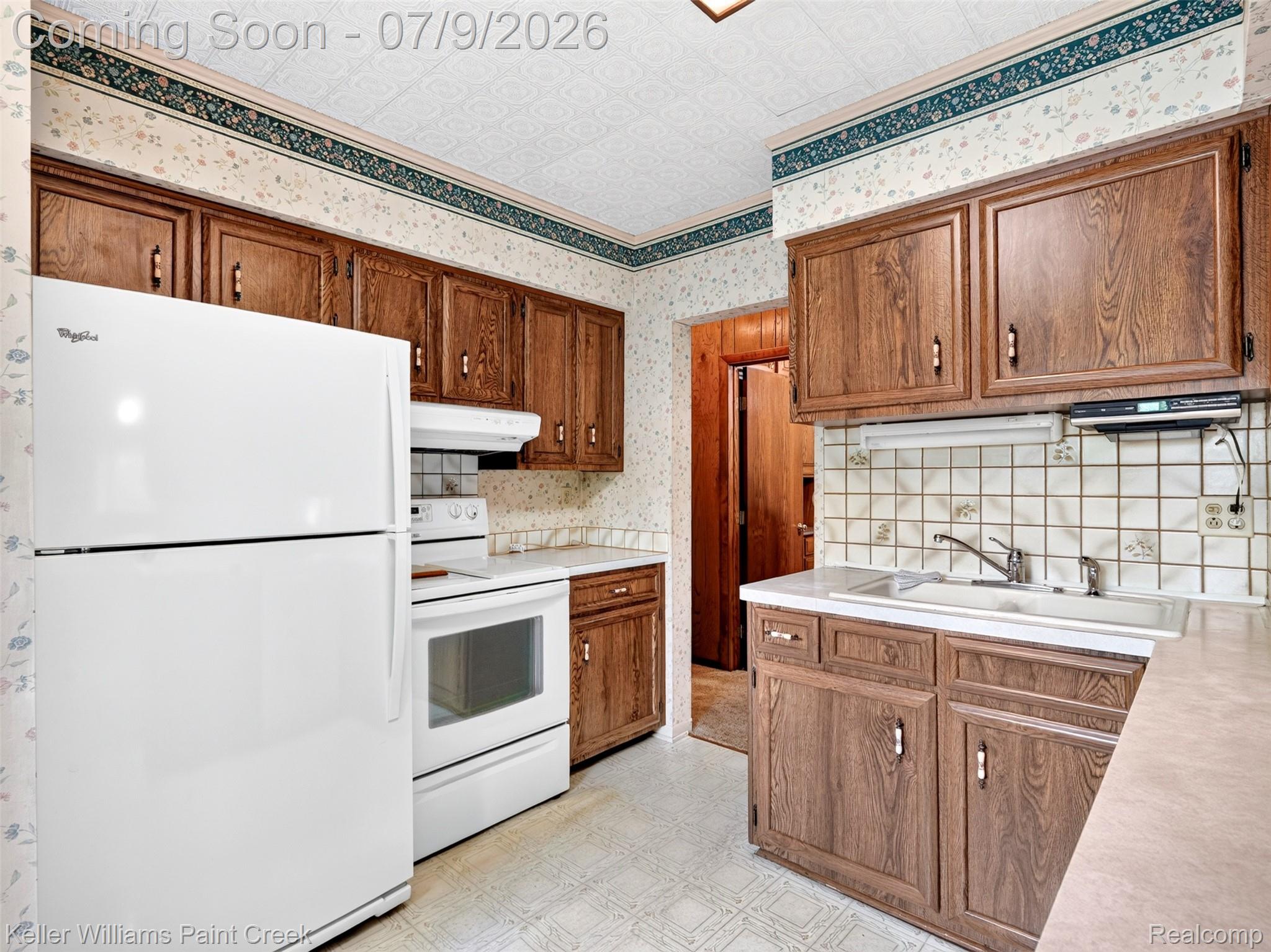 204 Russell Road Kawkawlin, MI 48631 - Photo 28 of 82 Kitchen featuring wood-finish cabinetry, white appliances, laminate countertops, and a tiled backsplash