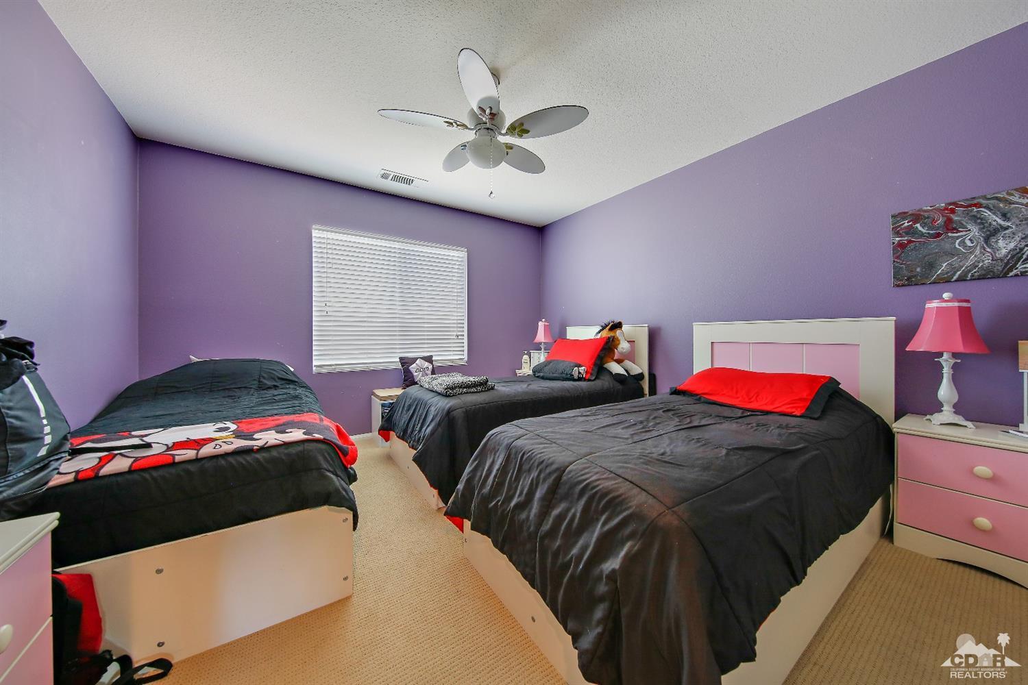 82734 Mount Riley Drive Indio, CA 92203 - Photo 17 of 26 a bedroom with two beds and a chandelier