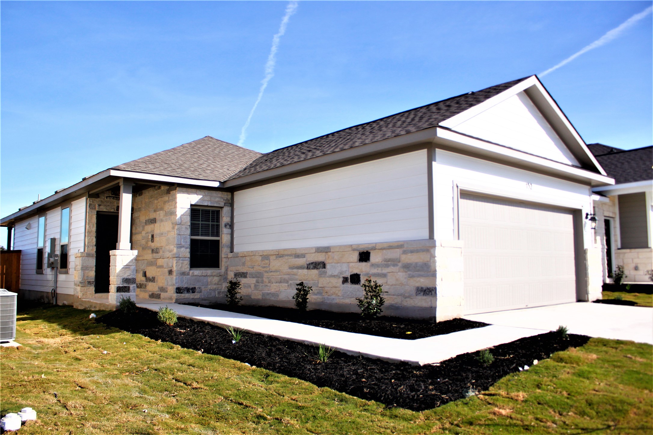 152 Old Stagecoach Road Jarrell, TX 76537 - Photo 2 of 21 View of front facade featuring stone siding, a garage, concrete driveway, a shingled roof, and a front lawn