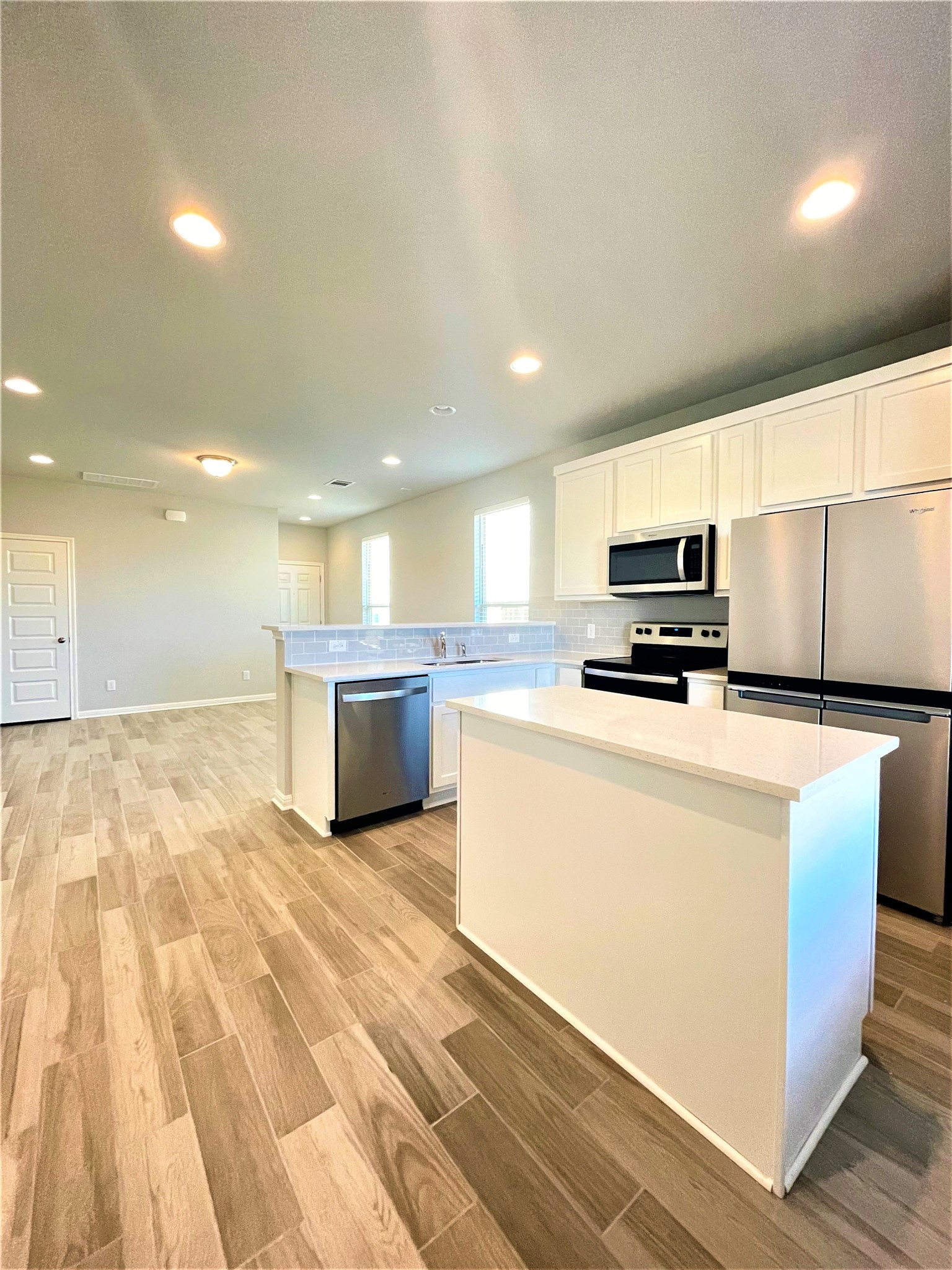 152 Old Stagecoach Road Jarrell, TX 76537 - Photo 6 of 21 Kitchen with stainless steel appliances, wood tiled floors, white cabinetry, and recessed lighting