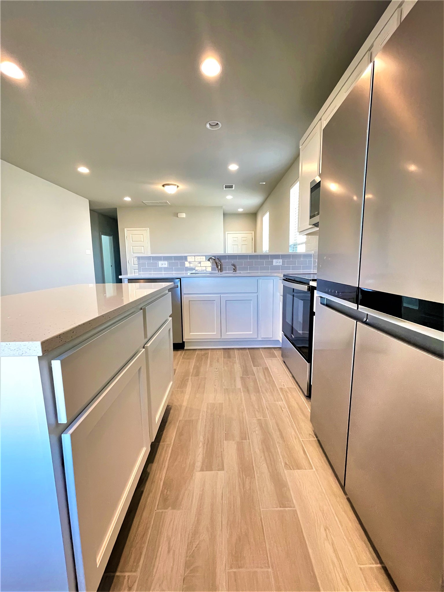 152 Old Stagecoach Road Jarrell, TX 76537 - Photo 7 of 21 Kitchen featuring stainless steel appliances, white cabinets, decorative backsplash, light wood finished floors, and a kitchen island