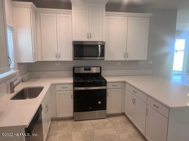 a kitchen with white cabinets and stainless steel appliances