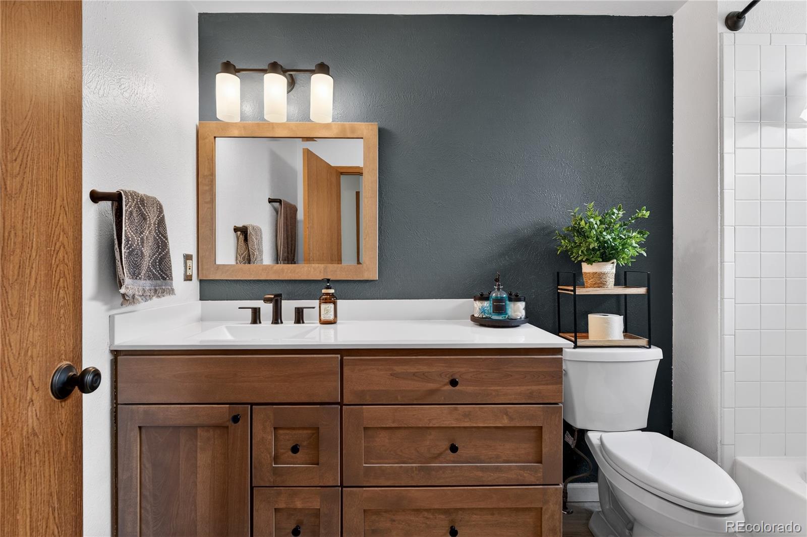 4730 Granby Way Denver, CO 80239 - Photo 19 of 27 a bathroom with a sink vanity mirror and toilet