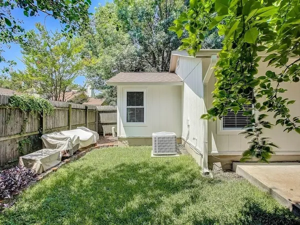 a backyard of a house with table and chairs and wooden fence