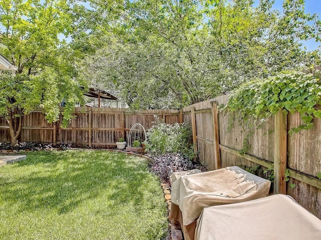 12909 Modena Trail Austin, TX 78729 - Photo 20 of 26 a backyard of a house with table and chairs and wooden fence